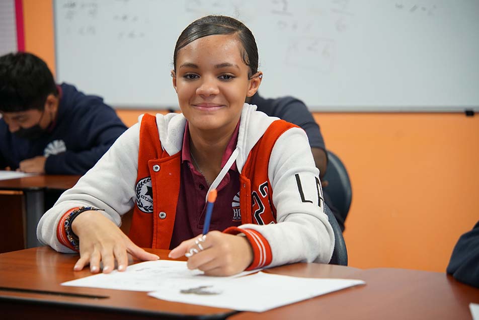 student in classroom smiling at camera