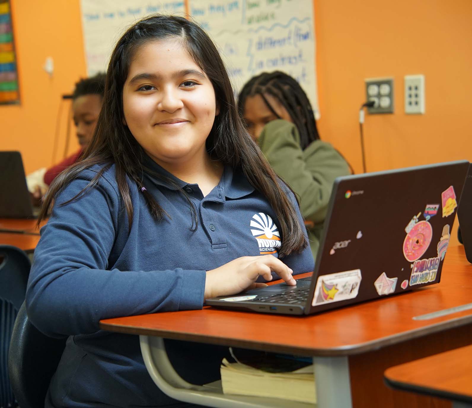 HSA Southwest student wearing headphones uses a laptop in class